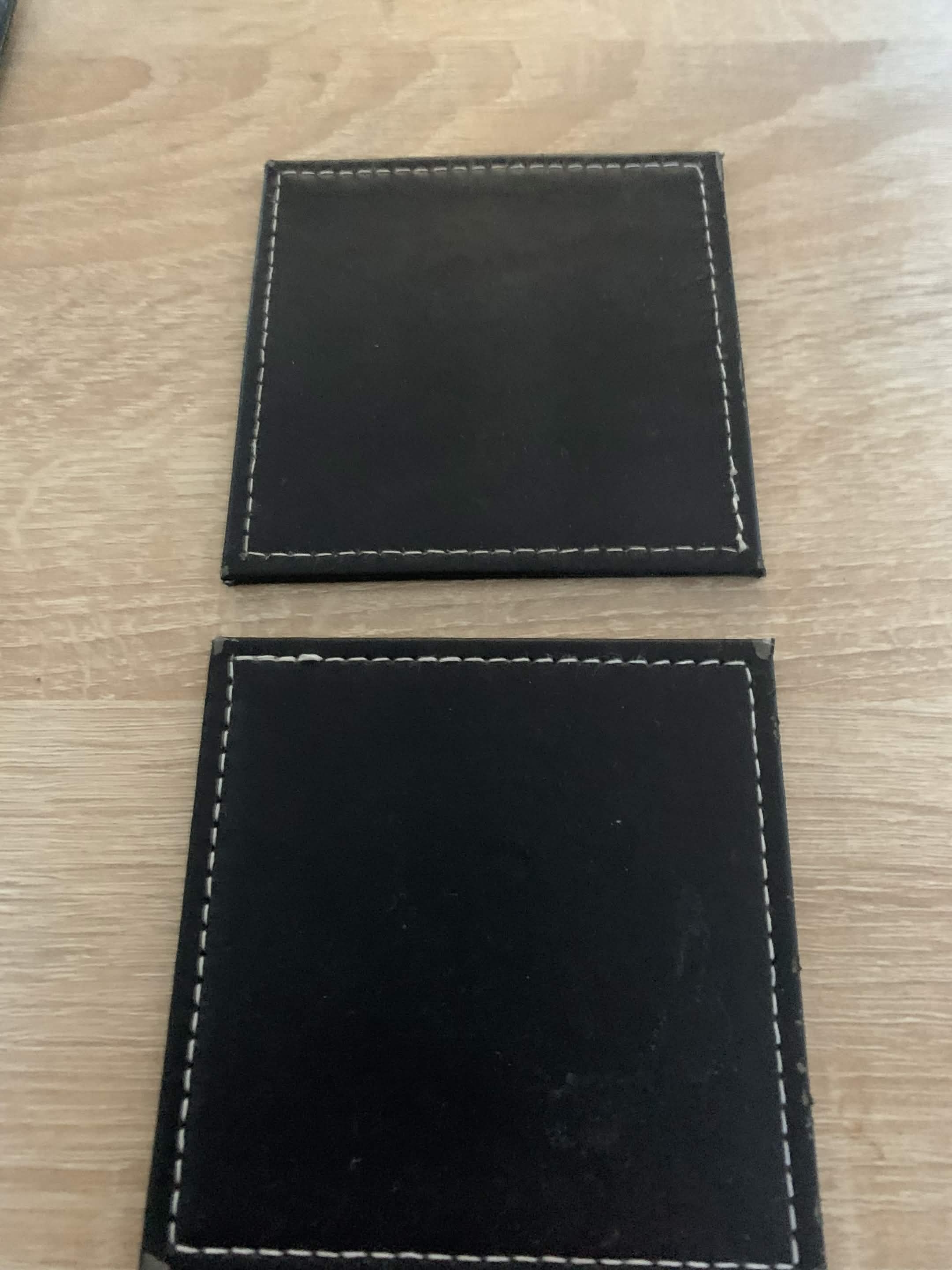Two black coasters on the table but arranged to resemble a Nintendo DS lying flat